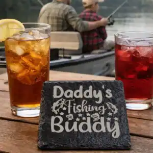 Daddy’s Fishing Buddy coaster in use with iced tea and juice at a lakeside fishing scene
